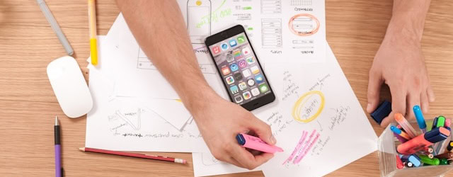 Person highlighting notes on marketing documents with a smartphone