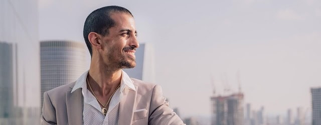Businessman in a light suit standing outdoors with a city skyline